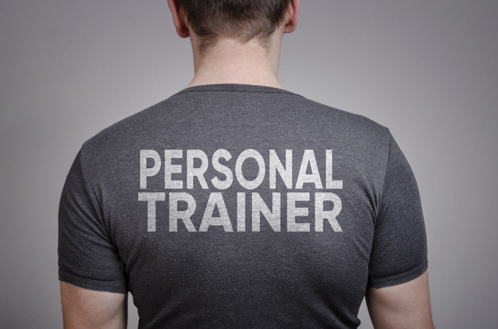 Personal trainer wearing branded workout shirt with logo while training a client in the gym